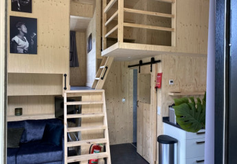 Innenraum eines Tiny House bei Bad Hoophuizen in den Niederlanden mit Holzdekor und kleinem Loft.