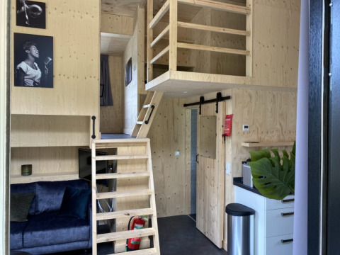 Innenraum eines Tiny House bei Bad Hoophuizen in den Niederlanden mit Holzdekor und kleinem Loft.