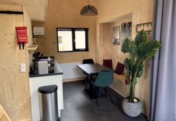 Modernes Tiny House Interieur in Bad Hoophuizen, Niederlande, mit Küche, Esstisch und Pflanze.