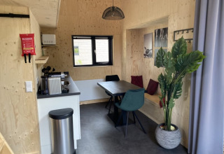 Intérieur de tiny house moderne à Bad Hoophuizen, Pays-Bas, avec cuisine, coin repas et plante.
