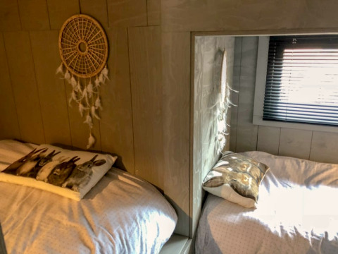 Deux lits confortables avec coussins d’animaux et un attrape-rêves dans la Tiny House de Bad Hoophuizen, Pays-Bas.