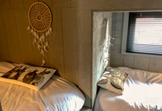 Deux lits confortables avec coussins d’animaux et un attrape-rêves dans la Tiny House de Bad Hoophuizen, Pays-Bas.