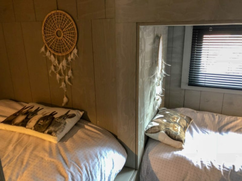 Zwei gemütliche Betten mit Tierkissen und Traumfänger in einem kleinen Raum des Tiny House in Bad Hoophuizen, Niederlande.