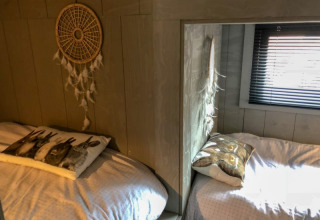 Zwei gemütliche Betten mit Tierkissen und Traumfänger in einem kleinen Raum des Tiny House in Bad Hoophuizen, Niederlande.