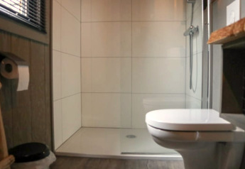 Modernes Badezimmer mit Toilette, Dusche und Holzboden in einem Tiny House in Bad Hoophuizen, Niederlande.