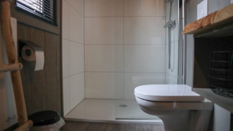 Modernes Badezimmer mit Toilette, Dusche und Holzboden in einem Tiny House in Bad Hoophuizen, Niederlande.