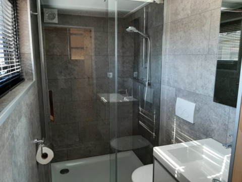 Bagno moderno e compatto con doccia in vetro, WC e lavabo in una tiny house a Bad Hoophuizen, Paesi Bassi.