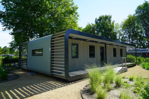 Moderne lodge Modus XL in het groen, met stijlvolle gevel en ruime ramen in de natuur.