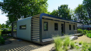 Moderne lodge Modus XL in het groen, met stijlvolle gevel en ruime ramen in de natuur.