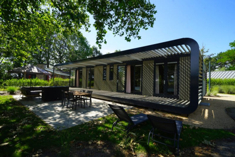 Modus XL Lodge in Bad Hoophuizen, Niederlande, mit moderner Terrasse und grüner Umgebung bei Sonnenschein.