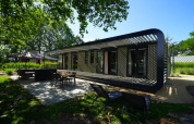Modus XL lodge in Bad Hoophuizen, Nederland, met een terras en groene, zonnige omgeving rondom.