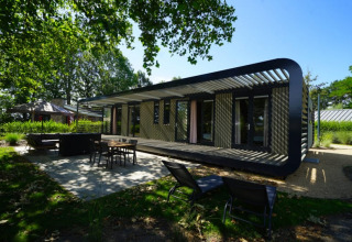 Modus XL lodge in Bad Hoophuizen, Nederland, met een terras en groene, zonnige omgeving rondom.