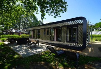 Modus XL lodge in Bad Hoophuizen, Nederland, met een terras en groene, zonnige omgeving rondom.