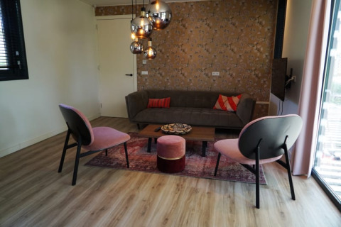 Woonkamer in Modus XL lodge in Bad Hoophuizen, Nederland, met moderne meubels en hanglampen.