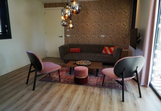 Soggiorno nel lodge Modus XL a Bad Hoophuizen, Paesi Bassi, con arredi moderni e lampade a sospensione.