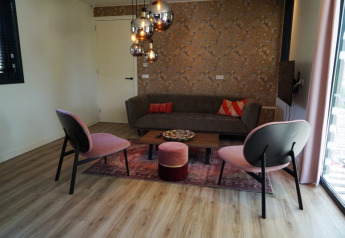 Soggiorno nel lodge Modus XL a Bad Hoophuizen, Paesi Bassi, con arredi moderni e lampade a sospensione.