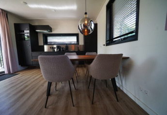Comedor moderno y cocina en la cabaña Modus XL en Bad Hoophuizen, Países Bajos, con interior elegante.
