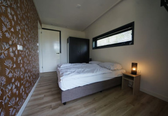 Slaapkamer in de Modus XL lodge in Bad Hoophuizen, Nederland, met tweepersoonsbed en minimalistische stijl.