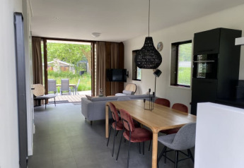 Moderne lodge interiør i Modus på Bad Hoophuizen, Holland, med spisebord, sofa og udendørs udsigt.