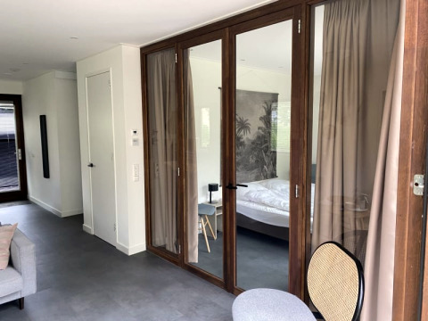 Lodge moderne à Modus à Bad Hoophuizen, Pays-Bas, avec portes vitrées, chambre et décoration élégante.