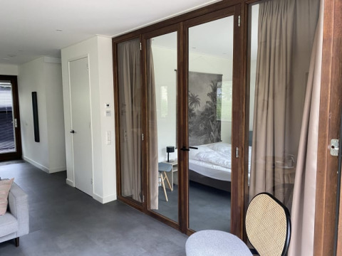 Lodge moderno en Modus, Bad Hoophuizen, Países Bajos, con puertas de vidrio y dormitorio elegante.