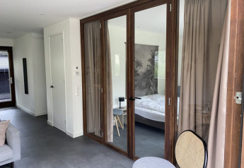 Moderne lodge bij Modus in Bad Hoophuizen, Nederland, met glazen deuren, slaapkamer en stijlvol interieur.