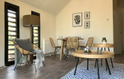 Sala de estar moderna en lodge Beach House en Bad Hoophuizen, Países Bajos, con zona de comedor y decoración natural.