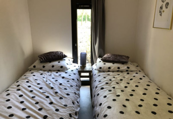 Twee enkele bedden met stippen dekbedovertrek naast een raam in Beach House te Bad Hoophuizen.