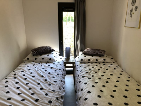 Zwei Einzelbetten mit gepunkteter Bettwäsche und Nachttisch in einem Zimmer im Beach House in Bad Hoophuizen.