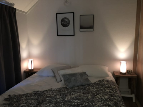 Slaapkamer in Beach House te Bad Hoophuizen, Nederland, met sfeerverlichting en moderne wanddecoratie.