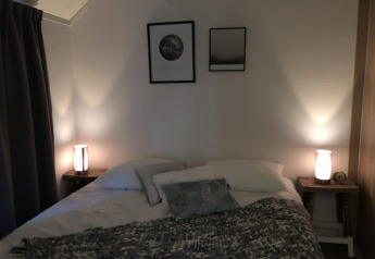 Knusse slaapkamer in Beach House in Bad Hoophuizen, Nederland, met lampen en twee ingelijste kunstwerken.