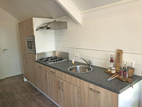 Cocina moderna en Beach House en Bad Hoophuizen, Países Bajos, con estufa, fregadero y alimentos.
