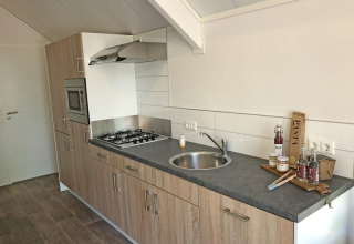 Cocina moderna en Beach House en Bad Hoophuizen, Países Bajos, con estufa, fregadero y alimentos.