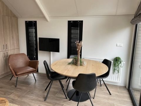 Eethoek in Tiny Beach House bij Bad Hoophuizen met ronde houten tafel, zwarte stoelen en kamerplanten.