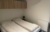 Dos camas individuales con ropa de cama blanca en un dormitorio minimalista en Tiny Beach House, Bad Hoophuizen, Países Bajos.