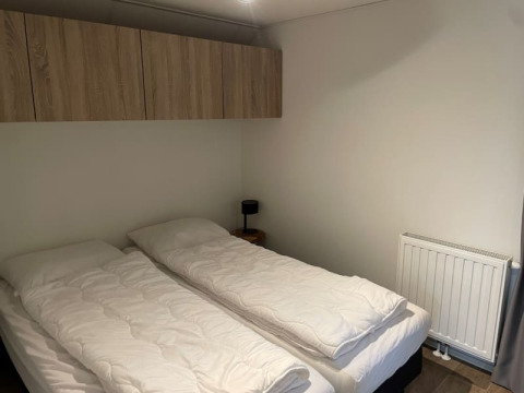 Dos camas individuales con ropa de cama blanca en un dormitorio minimalista en Tiny Beach House, Bad Hoophuizen, Países Bajos.