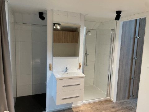 Baño moderno en Tiny Beach House, Bad Hoophuizen, Países Bajos, con ducha y lavabo blanco.