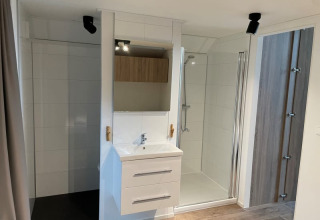 Baño moderno en Tiny Beach House, Bad Hoophuizen, Países Bajos, con ducha y lavabo blanco.