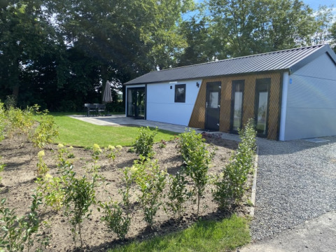 Moderne lodge Velthorst ved Bad Hoophuizen i Holland med have, terrasse og omgivet af grønne træer.