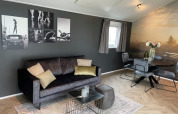 Trendy woonkamer in Velthorst-lodge te Bad Hoophuizen, Nederland, met kunst, sofa en eetruimte.
