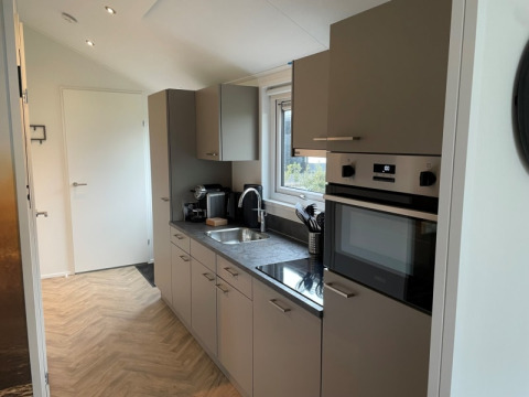 Interior de cocina moderna en una cabaña de Velthorst, Bad Hoophuizen, Países Bajos, con ventana y electrodomésticos.