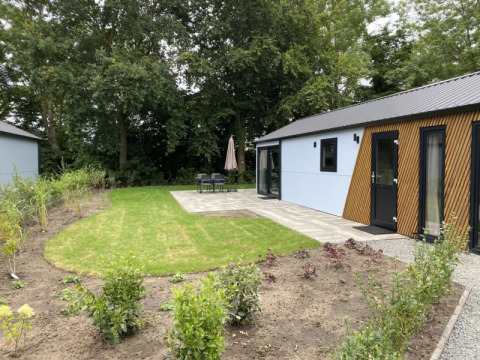 Vista exterior de la cabaña Velthorst en Bad Hoophuizen, Países Bajos, con jardín, césped y zona de terraza.