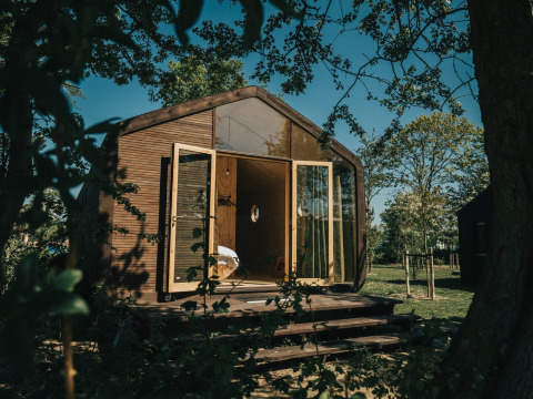 Wikkel Tiny House mit offenen Glastüren und Holzfassade, gelegen im Holiday Park De Klepperstee, Niederlande.