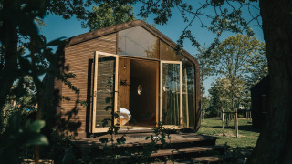 Tiny house Wikkel con porte in vetro aperte, rivestita in legno, al parco vacanze De Klepperstee nei Paesi Bassi.
