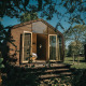 Wikkel tiny house med åbne døre og træbeklædning, omgivet af natur i Holiday park De Klepperstee, Holland.