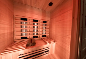 Infrarød sauna med træbænke og rullede håndklæder hos Modus Wellness i Bad Hoophuizen, Holland.