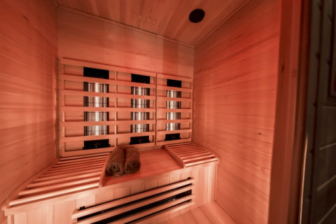 Sauna a infrarossi con panche in legno e asciugamani arrotolati presso Modus Wellness a Bad Hoophuizen, Paesi Bassi.