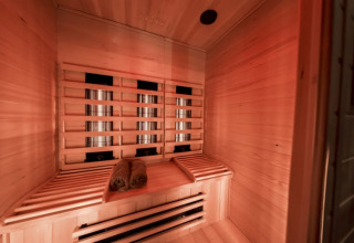 Sauna de infrarrojos con bancos de madera y toallas enrolladas en Modus Wellness, Bad Hoophuizen, Países Bajos.