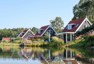 Vakantiepark met luxe glamping accommodaties langs een rustig meer, met charmante huisjes en natuur.