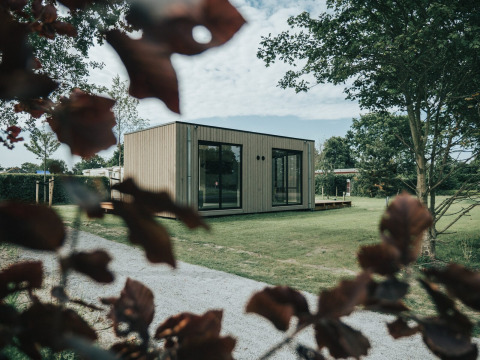 Modern lodgehuis met grote ramen op grasveld, bij Holiday park De Klepperstee in Nederland.